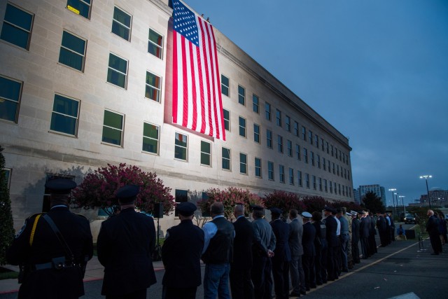 A Pentagon crew unfurls an American flag at dawn at the Pentagon on the 18th anniversary of the 9/11 attacks, Washington, D.C., Sept. 11, 2019.