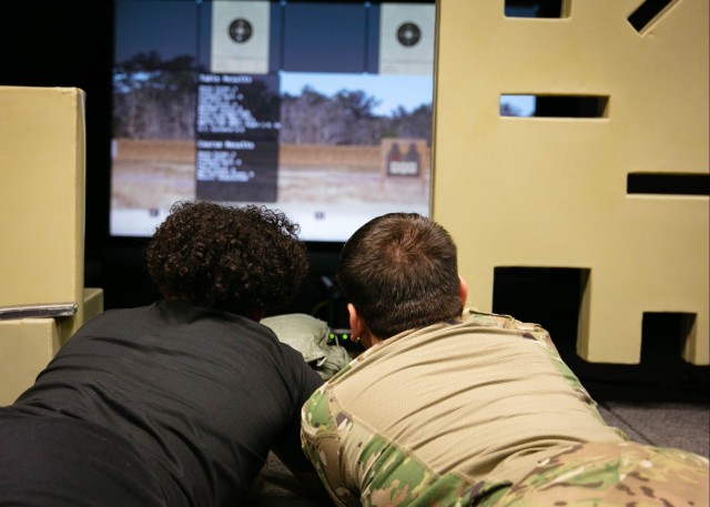 A Soldier trains a new recruit how to properly handle and fire a simulated weapon
