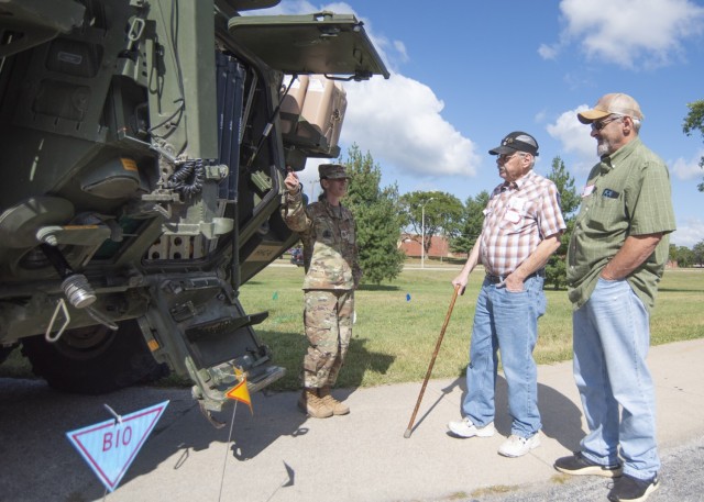 Retired Staff Sgt. Charles Mitchell (center) and his brother, Don, speak with Sgt. 1st Class Lynda Cooke, with Headquarters and Headquarters Company, 3rd Chemical Brigade, outside an M1135 Strycker vehicle Saturday at Nutter Field House during the Retiree Appreciations Days events. 