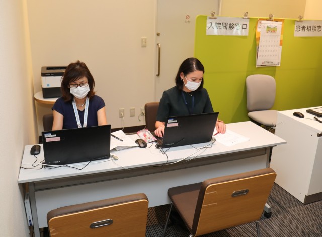 Mieko Yonaha, left, and Nozomi Akutsu, who are translators in the Civilian Health Care Navigator Program, sit at their desk inside the lobby of Zama General Hospital in Zama, Japan, Sept. 11, 2023. The program, which falls under U.S. Army Japan, will officially begin Oct. 2 to assist Department of Defense civilians, contractors and their dependents receive medical care at the hospital. 