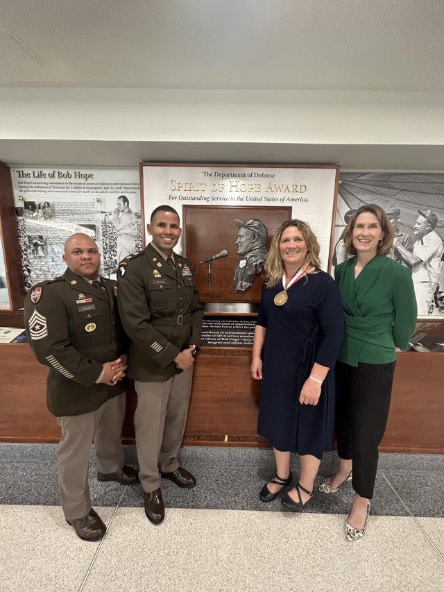 Spirit of Hope award winner Brenda Seubert poses in front of the Pentagon’s Spirit of Hope Award display with her command leadership from the 838th Transportation Battalion (left) and SDDC Deputy to the Commanding General Kristina O’Brien (right). 