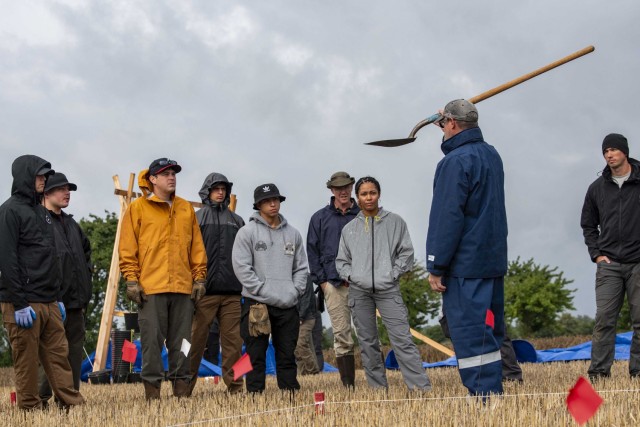 David Brown, a scientific recovery expert assigned to the Defense POW/MIA Accounting Agency, holds up a shovel as he instructs members of a recovery mission on excavation procedures in northern Germany, Aug. 3, 2023. Agency personnel conducted an excavation operation in an effort to find a U.S. aircraft crew lost over Germany during World War II.