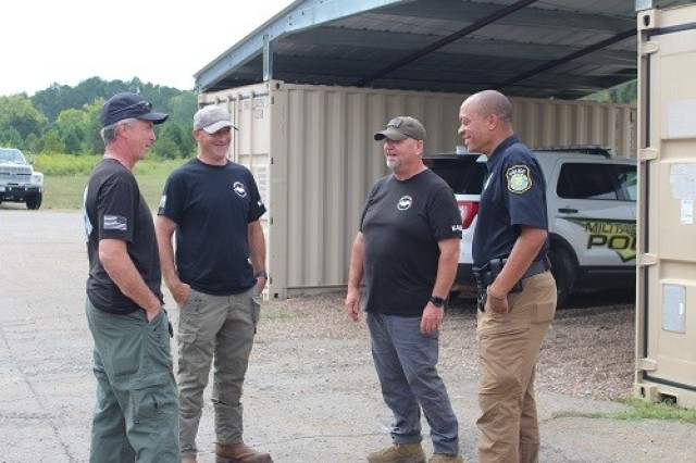 K-9 teams awaiting their turn to enter warehouse building 8026 for certification testing include, from left, Scott Hickey, Chad Smith and Chris Bailey, all of contractor Merrill’s Detector Dog Services LLC; and Marcel Chevalier of the Redstone police. 