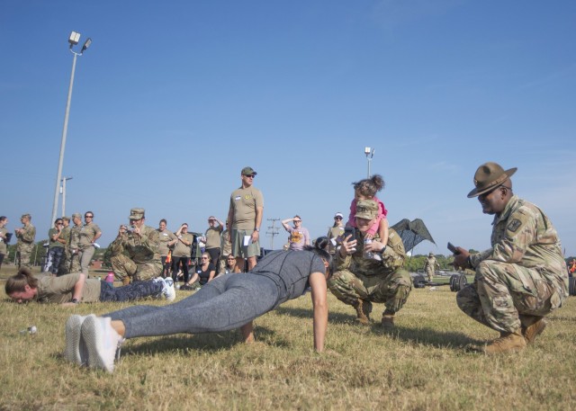 Lalita Jackson performs push-ups while her spouse, Capt. Terrance Jackson, with Headquarters and Headquarters Company, 14th Military Police Brigade,  and their daughter, Athena, look on Sept. 19 at Training Area 130.