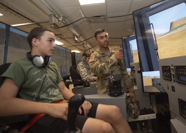 Staff Sgt. Firas Abuadra, an instructor with Company A, 554th Engineer Battalion, shows Marine Corps Junior ROTC Cadet Shawn Scoggins, from Pacific High School in Pacific, Missouri, how to operate one of the heavy equipment vehicle simulators...