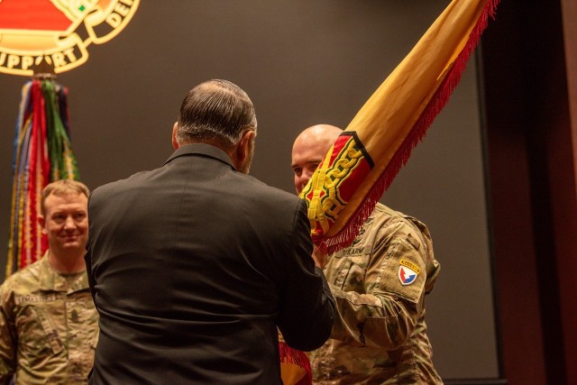 Command Sgt. Maj. James Brasher passes the flag to IMCOM Sustainment Director Davis Tindoll as Brasher relinquishes responsibility as the directorate’s command sergeant major. Looking on is Garrison Command Sgt. Maj. Dylan Lemasters. 
