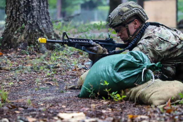 Spc. Shane Moon, a native of Cleveland, Ohio, representing Army Cyber Command reacts to direct fire during the patrol lanes portion of the 2023 Army Best Squad Competition at Fort Stewart, Georgia, Sept. 27, 2023. The Warrior Ethos states, &#34;I...