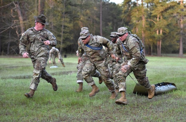 Infantry recruits with Bravo Company, 1st Battalion, 50th Infantry Regiment, compete in a medical-evacuation race during the First 100 Yards at Fort Benning, Georgia, March 30, 2023. The 90-minute event teaches new recruits how to quickly work together to accomplish the mission.