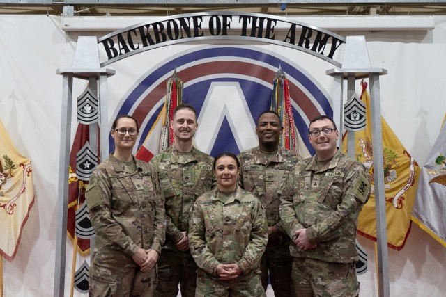 U.S. Army Reserve Master Sgt. Jennifer Kelly (center), chief paralegal noncommissioned officer, 143d Expeditionary Sustainment Command, stands with newly inducted NCOs with the office of the command judge advocate for a group photo in front of the NCO arch at the NCO induction ceremony at Camp Beuhring, Kuwait. The fell under 1st Theater Sustainment command when it implemented its Leading Individuals From Experience coaching program. The program aims to enhance NCOs&#39; leadership capabilities and equip Soldiers with the necessary skills and knowledge to lead in the Army of 2030 and beyond. (U.S. Army Reserve photo by Capt. Katherine Alegado)