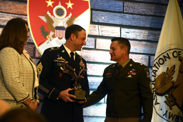 Sgt. Maj. of the Army Michael R. Weimer presents the Sgt. Maj. Larry Strickland Educational Leadership Award to Sgt. Maj. Benjamin Buzek during the Sergeant Major of the Army Forum and Awards ceremony at the Association of the U.S. Army Annual Meeting and Exposition in Washington, D.C., Oct. 9, 2023.