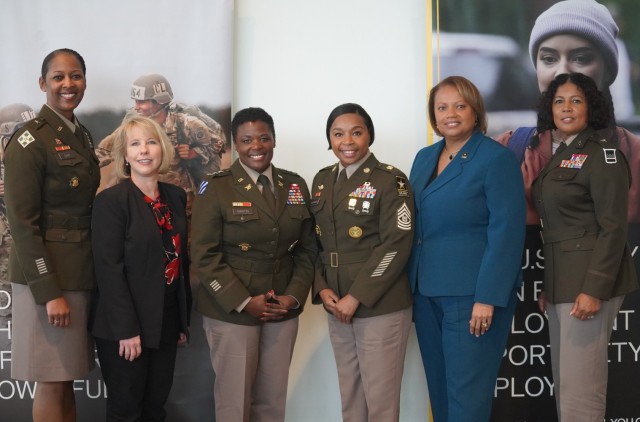 Members of the “‘Be All You Can Be’: Achieving Your Professional Goals” panel pose in front of Army displays. 