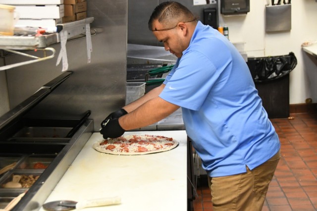 YPG Family, Morale, Welfare and Recreation (FMWR) Programs and Services Assistant Business Manager Jose Garcia makes a pizza in the kitchen at the Coyote Lanes Bowling Alley, which he later delivered to a Marine at the FOB at Laguna Airfield.