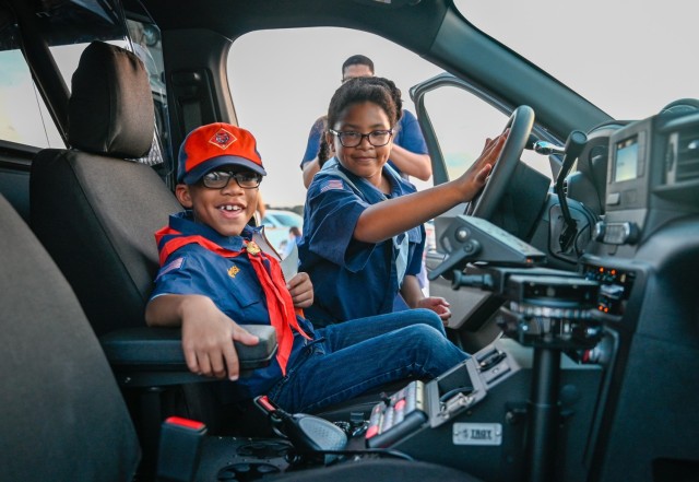 Phoenix and Aliyah Wilcock enjoy their time inside a Fort Cavazos military police car, delighting in pushing buttons to activate the sirens during the National Night Out event Oct. 3, 2023, at Phantom Warrior Stadium. (U.S. Army photo by Eric Franklin, Fort Cavazos Public Affairs)