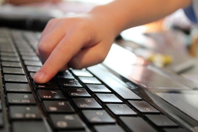 Child's finger pressing a key on laptop. Close up keyboard, Kid on blurred backgound. Children in Internet. Information security