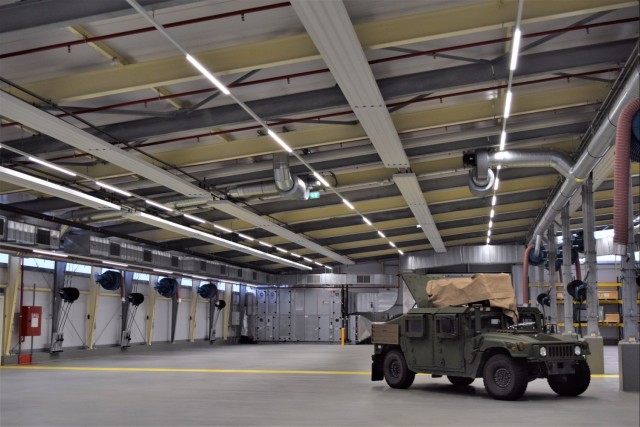 Renovations at APS-2 Zutendaal: A warehouse showcasing new radiant heat panels and LED lights as well as a military vehicle. 