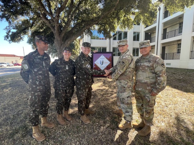 [Center Right] U.S. Army Environmental Command Commander Col. Mathew F. Kelly, and Command Sgt. Maj. Francisco Cardenas, present a ceremonial gift from USAEC to Col. Andreos Souza, Deputy Director, Brazilian Army Real Estate and Environment Directorate (DPIMA), Lt. Thaysa Friaça Leite, environmental engineer, DPIMA, and Commander Col. Sergio Matos, Brazilian Army liaison officer to U.S. Army South, Oct. 18, 2023. The Brazilian delegation presented a gift to USAEC command as well as a gesture of the bond forged and shared global commitment to environmental stewardship by both Brazil and the U.S. 