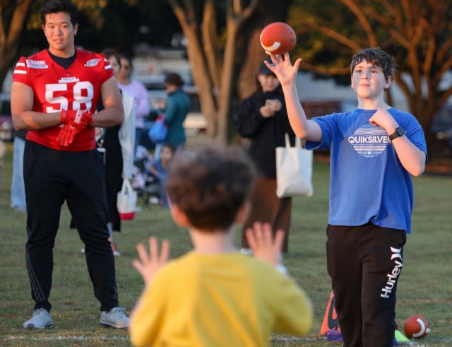 A volunteer passes a football to a participant during a youth sports clinic at Sagamihara Family Housing Area, Japan, Nov. 3, 2023. The clinic, which had about 150 American and Japanese children attend, was the first event jointly hosted by U.S. Army Garrison Japan and Zama Junior Chamber International. 