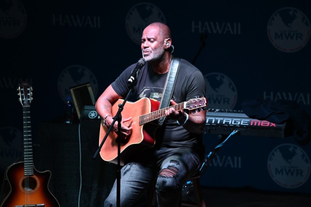 Grammy-nominated artist Brian McKnight delivers an emotional performance of &#34;Red, White, and Blue,&#34; his final song of the night, dedicated to the service members and their families at Schofield Barracks. Seated center stage with his custom-built guitar, McKnight&#39;s soulful tribute resonates through a crowd of America&#39;s finest, echoing his appreciation for their sacrifice and dedication.