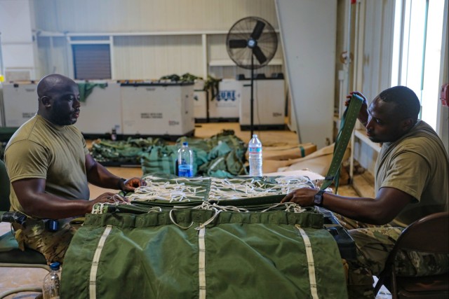 U.S. Army Parachute Riggers prepare to tie rigged equipment