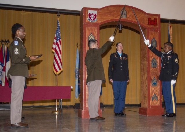 Sgt. Bridget Olenik, 399th Army Band, pauses under the ceremonial archway during an NCO induction ceremony Friday in Abrams Theater, where 21 NCOs from across the installation were welcomed into the NCO Corps.