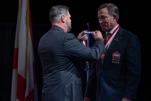 Retired Cmdr. Clay Davis, president of the Madison County Military Heritage Commission, presents a medal to Will Johnson during his induction into the Hall of Heroes, Nov. 10.  