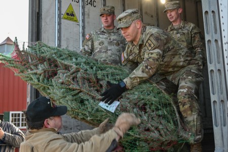 Volunteers pass a tree to New York Army National Guard Spc. Matthew Clark, a recruiting assistant assigned to the 466th Area Support Medical Company, onto a FedEx truck during the annual Trees for Troops loadup event in Ballston Spa, New York, November 28, 2023. The event has been hosted at Ellms Tree Farm for the last 19 years, sent 131 donated trees to military installations around the world for the holidays, including Fort Drum, Fort Hamilton, and West Point here in New York.