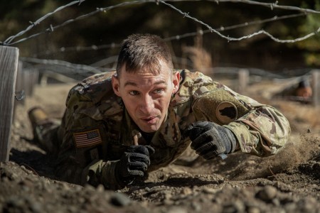 Army Staff Sgt. Corey Rogers low-crawls under barbed wire during the Wolf Cup Competition at Devens Reserve Forces Training Area, Mass., Oct. 14, 2023. The competition tested competencies in basic Army warrior tasks.