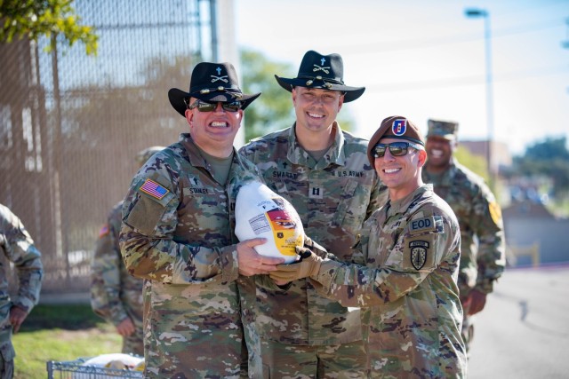Chaplain (Capt.) Robert Stanley, 3rd Battalion, 16th Field Artillery Regiment, 2nd Armored Brigade Comat Team, 1st Cavalry Division; Chaplain (Capt.) Christopher Smartt, 1st Battalion, 8th Cavalry Regiment, 2nd ABCT, 1st Cav. Div.; and Chief Warrant Officer 2 Nickolas Webb, 3rd Security Force Assistance Brigade, post with a turkey before giving it away Nov. 15. (U.S. Army photo by Blair Dupre, Fort Cavazos Public Affairs)