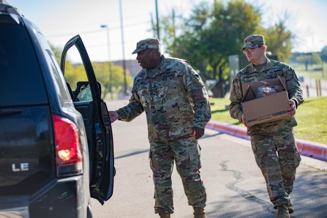 Command Sgt. Maj. Calvin Hall, U.S. Army Garrison-Fort Cavazos command sergeant major, and Spc. Bryce Popken, 2nd Battalion, 8th Cavalry Regiment, put a basket filled with fixings into a vehicle Nov. 15 during the giveaway. (U.S. Army photo by...