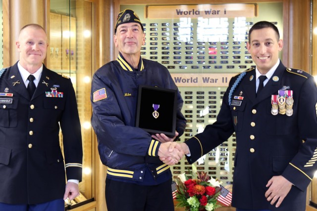 Maj. Eric Van Hout, an administrative officer with the Wisconsin Army National Guard’s 2nd Battalion, 127th Infantry Regiment, and Command Sgt. Maj. Ryan Johnson, battalion command sergeant major, present a Purple Heart medal to Mike Muthig, the...