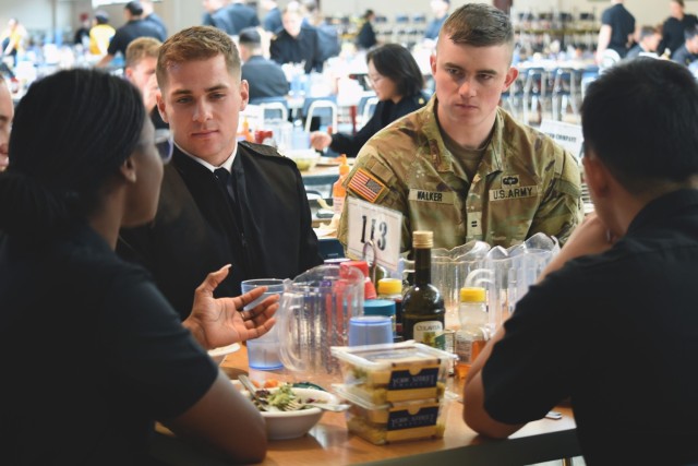 U.S. Naval Academy Midshipman Nick Janowsky and U.S. Military Academy Cadet Mitch Walker listen to Midshipman Jacey Akpokli as she talks about a class during lunch Dec. 1. Walker participated in the semester-long service academy exchange program and will be one of seven West Point students exchanged at midfield prior to the Army-Navy game Dec. 9.