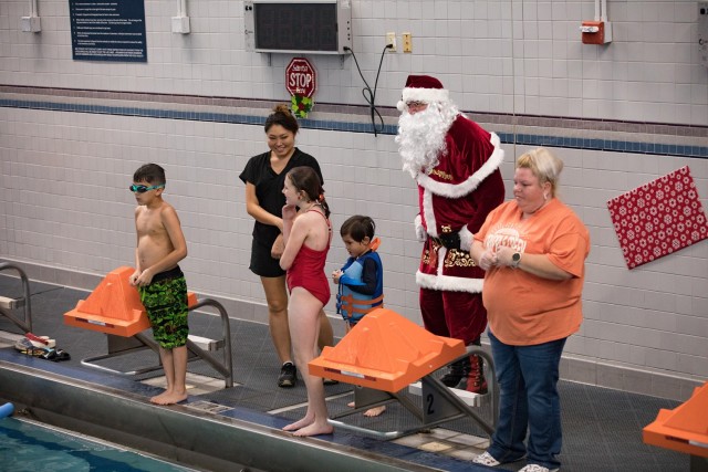 Santa strategizes with swimmers who are about to take on the floating obstacle course during the Swimming with Santa event Dec. 2 at Abrams Physical Fitness Center. (U.S. Army photo by Blair Dupre, Fort Cavazos Public Affairs)