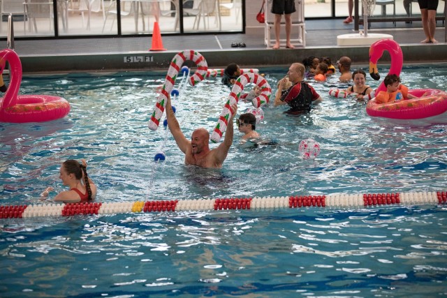 Families splash around the indoor pool Dec. 2 at Abrams Physical Fitness Center with candy cane-shaped floaties. (U.S. Army photo by Blair Dupre, Fort Cavazos Public Affairs)