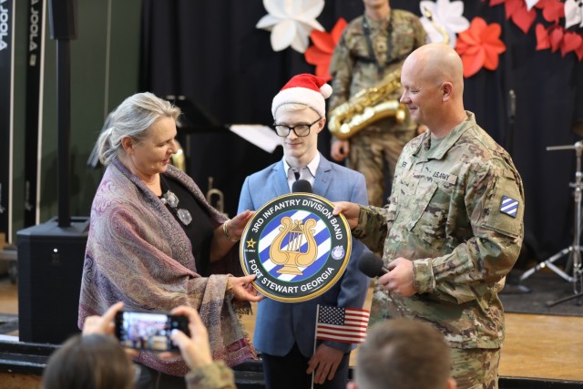 Warrant Officer Timothy Rogers, the commander of the U.S. Army’s 3rd Infantry Division Band, presents a 3rd Infantry Division drum cover to Ewa Bernacka, a teacher at the Krakow School for the Blind, following a performance and music workshop for students in Krakow, Poland, Dec. 7, 2023. The 3rd Infantry Division’s  mission in Europe is to engage in multinational training and exercises across the continent, working alongside NATO Allies and regional security partners to provide combat-credible forces to V Corps, America’s forward deployed corps in Europe. (U.S. Army photo by Maj. Joe Trovato)