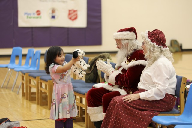 A young child shows her new toy to Santa and Mrs. Claus during Operation Santa Claus at the Martin L. Olson School gymnasium in Golovin, Alaska, Nov. 30, 2023. Operation Santa Claus is the Alaska National Guard’s yearly community outreach program that provides gifts and Christmas cheer to children in remote communities across the state. 