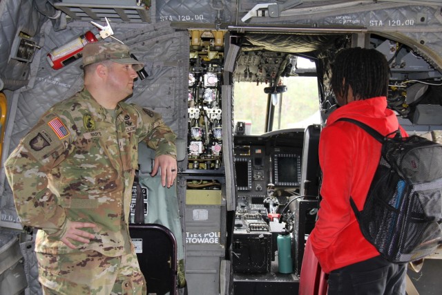 Staff Sgt. Michael Buys, CH-47 Flight Engineer, explains the workings of the Chinook to a student from  Hillcrest High School in Conecuh County, Alabama at the Hometown Heroes Army Recruiting event on Dec. 8, 2023.