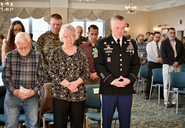CSM Traylor, alongside his mother and stepfather, bows his head during the chaplain’s invocation during his retirement ceremony at the Weckerling Center, Presidio of Monterey, Calif., Dec. 12.
