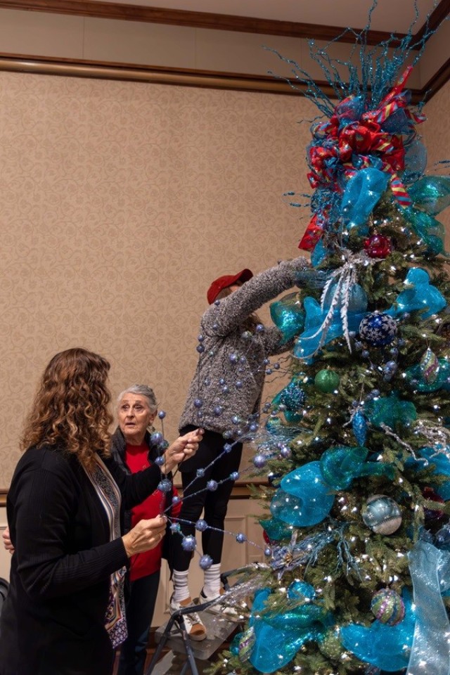 Fern Brazda, left, Atty Allred and Mia Myers work together to decorate a tree at The Summit. 