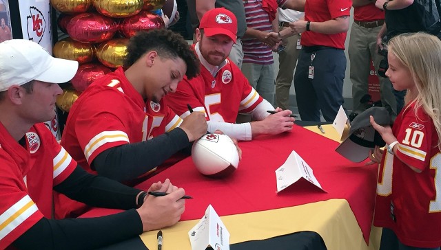 Kansas City Chiefs rookie quarterback Patrick Mahomes, joined by fellow quarterbacks Matt McGloin and Chad Henne, signs a football for 8-year-old Madison Fuller during a meet-and-greet autograph opportunity May 16, 2018, at the Fort Leavenworth...