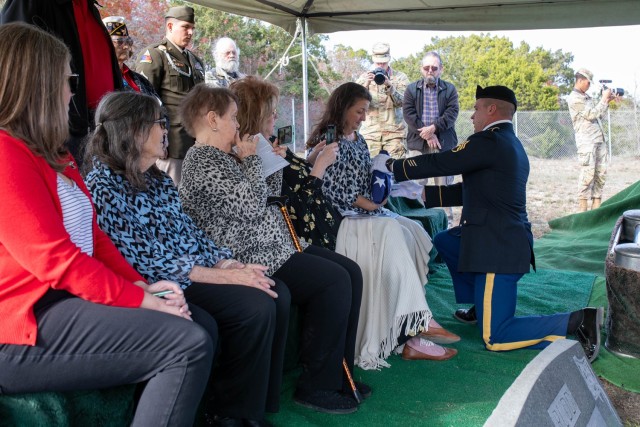 Staff Sgt. Kyle Peavler, 1st Cavalry Division Artillery, presents an American flag to Teri Olivier, a great-niece of Staff Sgt. Robert G. Rudd Dec. 9 at Bethel Cemetery while the rest of the family watches. Rudd, killed during the Battle of the Bulge, was finally laid to rest after 78 years.