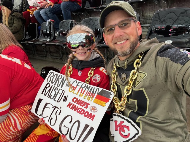 Thirteen-year-old Maddie Fuller, aka Goggle Girl, displays a sign celebrating her heritage while her father, retired Command Sgt. Maj. Mike Fuller, Fort Leavenworth Garrison human resources director, takes a photo at a Kansas City Chiefs game...