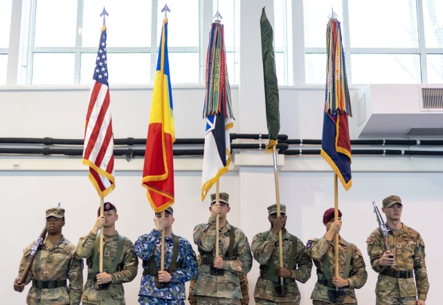 U.S. Army paratroopers from the 82nd Airborne Division, "Task Force 82", soldiers from the 10th Mountain Division, "Task Force Mountain", and regional military defense counterparts, stand at attention with their unit colors during the V Corps hosted transfer of authority ceremony at Mihail Kogalniceanu Air Base, Romania, Dec. 15. The soldiers and paratroopers assigned to TF 82 support the U.S. Army V Corps’ mission to reinforce NATO’s eastern flank, assure European allies and partners, and deter aggression.