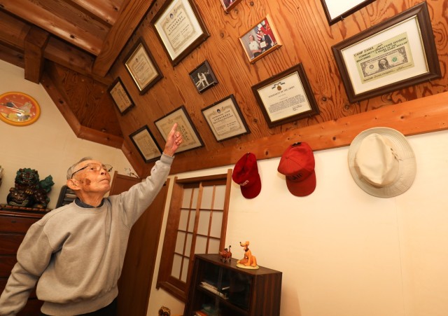 Tsuneo Yamagishi, 95, points to a wall where he has several certificates honoring his achievements on display inside his home in Sagamihara, Japan, Dec.  5, 2023. Yamagishi, who previously served in the Japanese Imperial Navy, eventually worked more than 50 years at U.S. Army installations following World War II. 