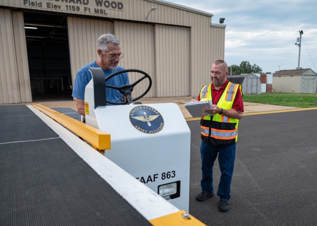 John Yohn (right), an air traffic assistant at Fort Leonard Wood’s Forney Airfield – and the master driver for the Directorate of Plans, Training, Mobilization and Security – performs annual sustainment training on a baggage loader vehicle...