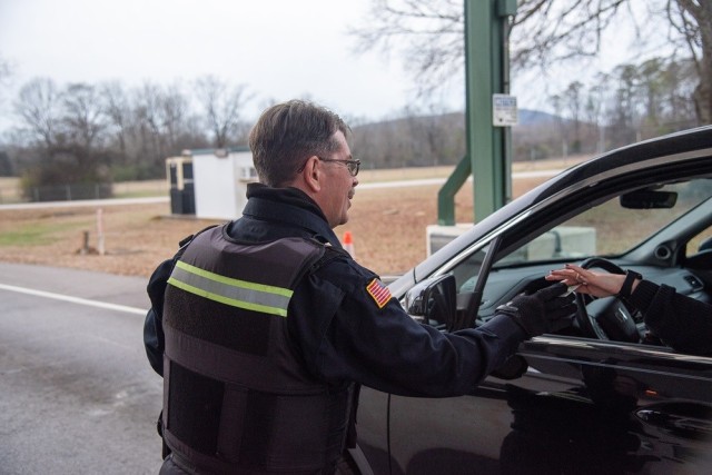 Rodger D. Smith, a guard at Redstone Arsenal, checks the credentials of a motorist Friday afternoon.  