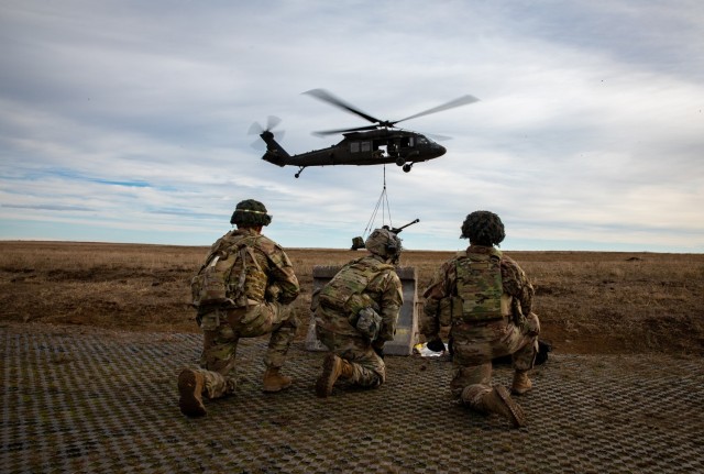 Artillery Soldiers from Bravo Battery, 3rd Battalion, 320th Field Artillery Regiment, 3rd Brigade Combat Team, 101st Airborne Division conduct sling-load operations and elevator drills with 3rd Attack Helicopter Battalion, 1st Aviation Regiment, 1st Combat Aviation Brigade, 1st Infantry Division on Mihail Kogalniceanu Air Base, Romania, Jan. 4, 2024, to increase readiness and proficiency in air assault operations. (U.S. Army photo by Pfc. Aiden O'Marra)