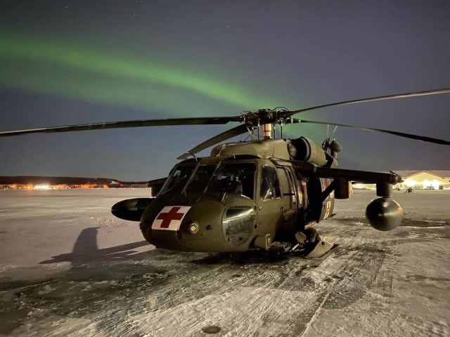 A UH60L Blackhawk helicopter belonging to Charlie Company, 1-52 General Support Aviation Battalion, 16th Combat Aviation Brigade, is parked on the airfield  at Fort Wainwright while its crew prepares for a mission. The aurora borealis puts on a show overhead. (Cg)