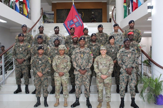 Sgt. Maj. Esmeralda Vaquerano, G-1 (personnel) Sergeant Major for the D.C. Army National Guard and Sgt. Jessica A. Frazer, Recruitment and Retention Battalion, D.C. Army National Guard stand with members of the Jamaica Defence Force (JDF) for a group photo during a State Partnership Program visit to the Caribbean Military Academy (CMA), Dec. 12-14, 2023. D.C. Guard members participated in an NCO Career Development Subject Matter Expert Exchange (SMEE) which included reviewing training, promotions, leadership, duties and responsibilities of NCOs with JDF’s Jamaica Regiment, Support Brigade, and the Martitime, Air and Cyber Command (MACC).