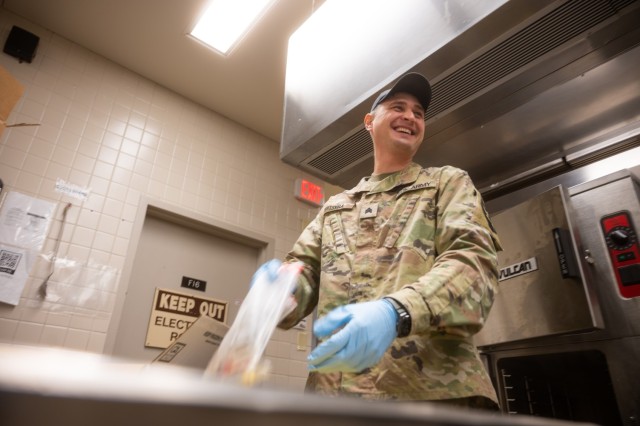 U.S. Army Sgt. Dmytro Tsvira, a culinary specialist assigned to 296th Brigade Support Battalion, laughs while preparing food for the Ghost Bistro Dining Facility at Joint Base Lewis McChord, Washington, Jan. 10, 2024. Tsvira prepared corn, meat...