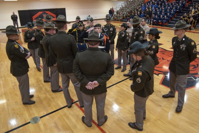 Fort Leonard Wood drill sergeants and training instructors surround and observe the final two competitors – cadets Matthew Doyle (right), from Central High School, in St. Joseph, Missouri, and Gabrielle Carnoali, from Leavenworth High School, in...